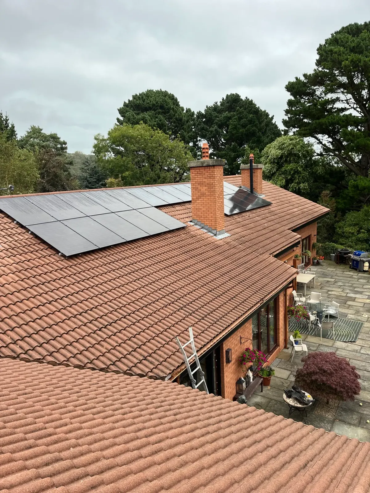 Solar panel installation on a large detached house in a mature garden setting