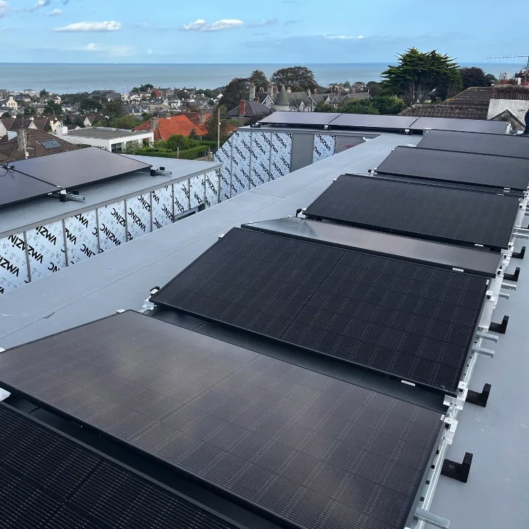 Ballasted solar array across a flat commercial roof overlooking Dublin Bay
