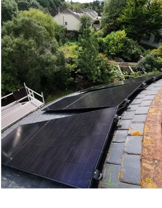 Solar panels on a slate roof overlooking a mature garden