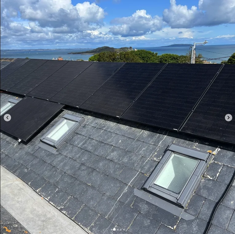 Solar panels fitted around roof windows on a slate roof overlooking Dublin Bay