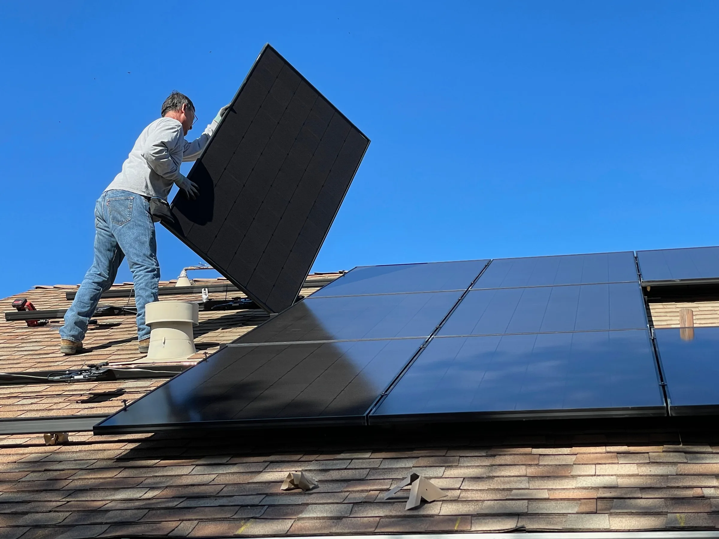 Installer carrying a panel into position on a roof